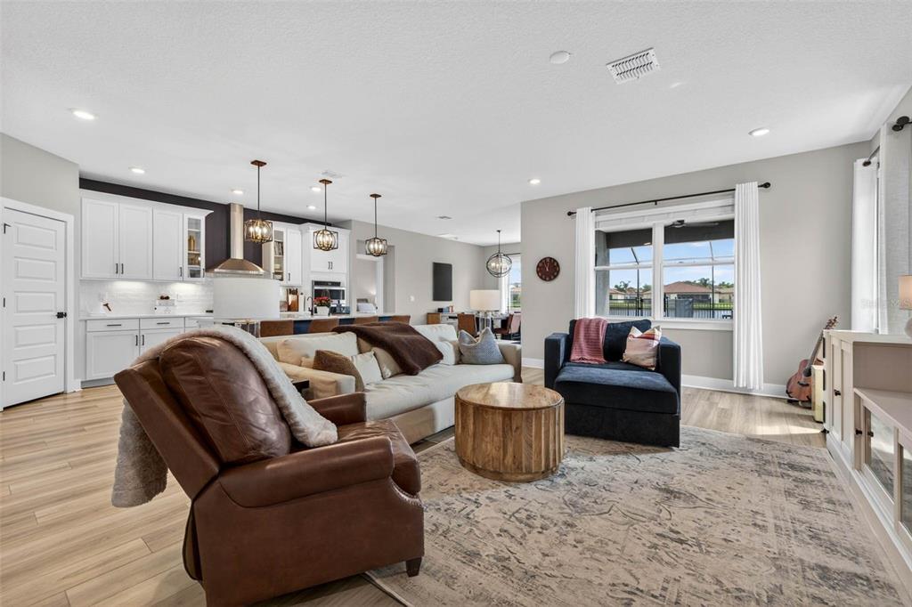 A living room with a brown leather recliner, a sofa, and an open-concept kitchen — 3709 SAVANNA PALMS COURT, BRADENTON, FL