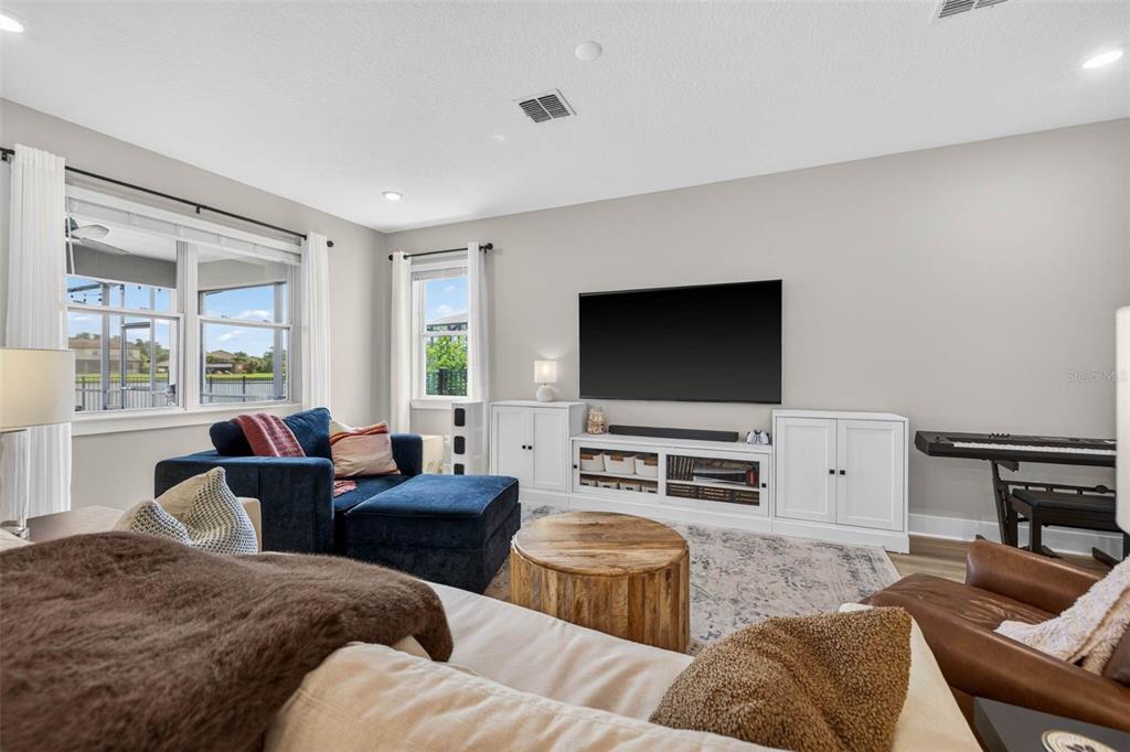 A living room features a blue sectional, a wooden coffee table, and a wall-mounted television — 3709 SAVANNA PALMS COURT, BRADENTON, FL