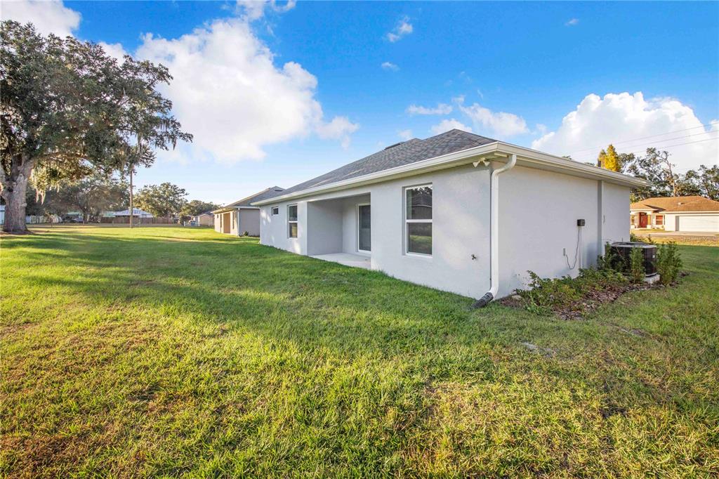 The exterior of a light-colored house features a small covered patio and a grassy yard — 500 9TH STREET NE, FORT MEADE, FL