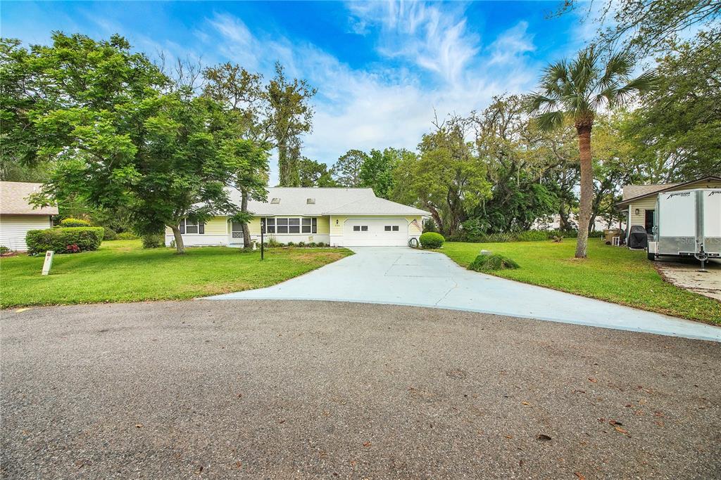 A yellow single-story house with a two-car garage and a paved driveway — 335 RIVER GLASS COURT, LEESBURG, FL