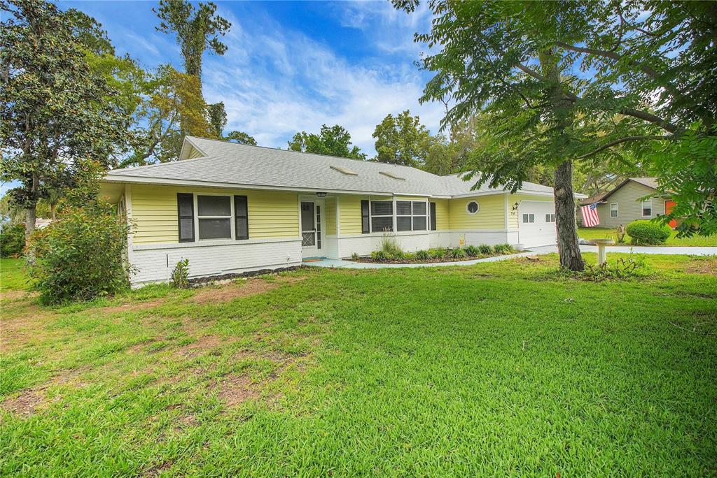 A yellow, single-story house with a white brick base and a two-car garage — 335 RIVER GLASS COURT, LEESBURG, FL