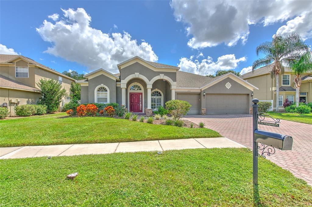 An aerial view shows three suburban houses with brown roofs situated along a small lake — 4752 PATAGONIA PLACE, LAND O LAKES, FL