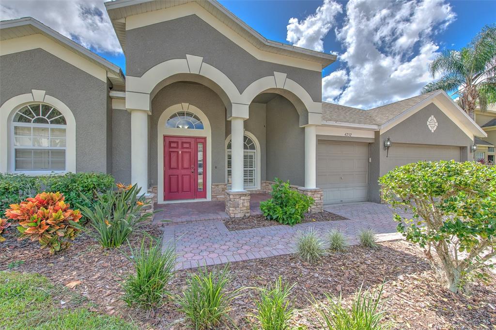 A covered patio with a ceiling fan, gray concrete flooring, and multiple sliding glass doors — 4752 PATAGONIA PLACE, LAND O LAKES, FL