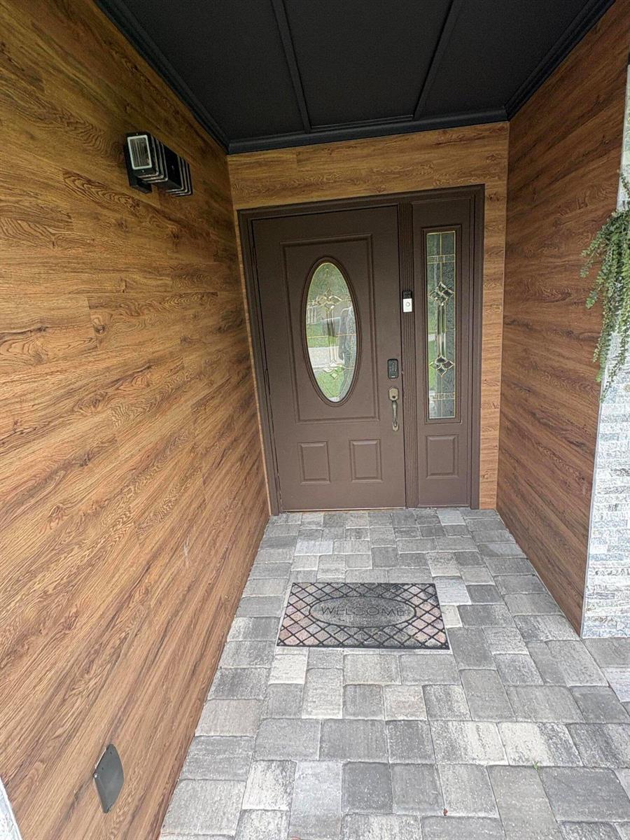 A front entryway features wood-look wall paneling, a brown door with glass, and paver flooring — 3501 Boulevard Boulevard, Delray Beach FL 33445, DELRAY BEACH, FL
