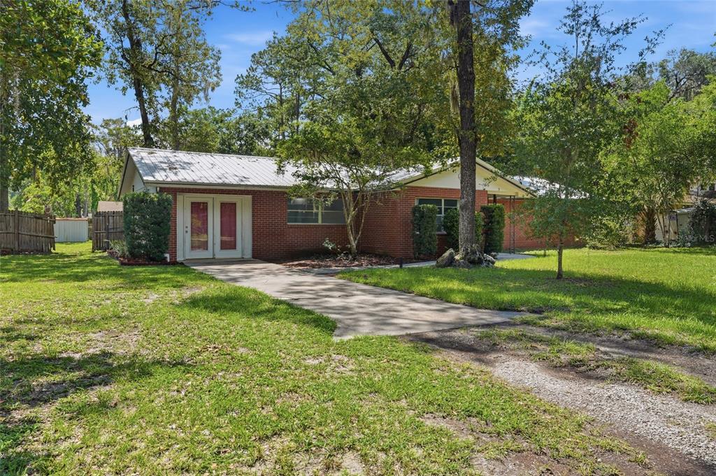 A single-story red brick house with a metal roof and a concrete driveway — 5 SW 41ST STREET, GAINESVILLE, FL