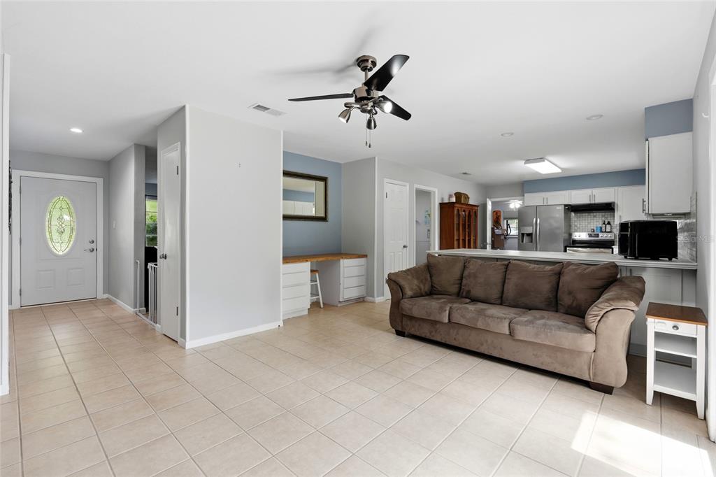 A living room with tile flooring, a brown sofa, and an open kitchen in the background — 5 SW 41ST STREET, GAINESVILLE, FL