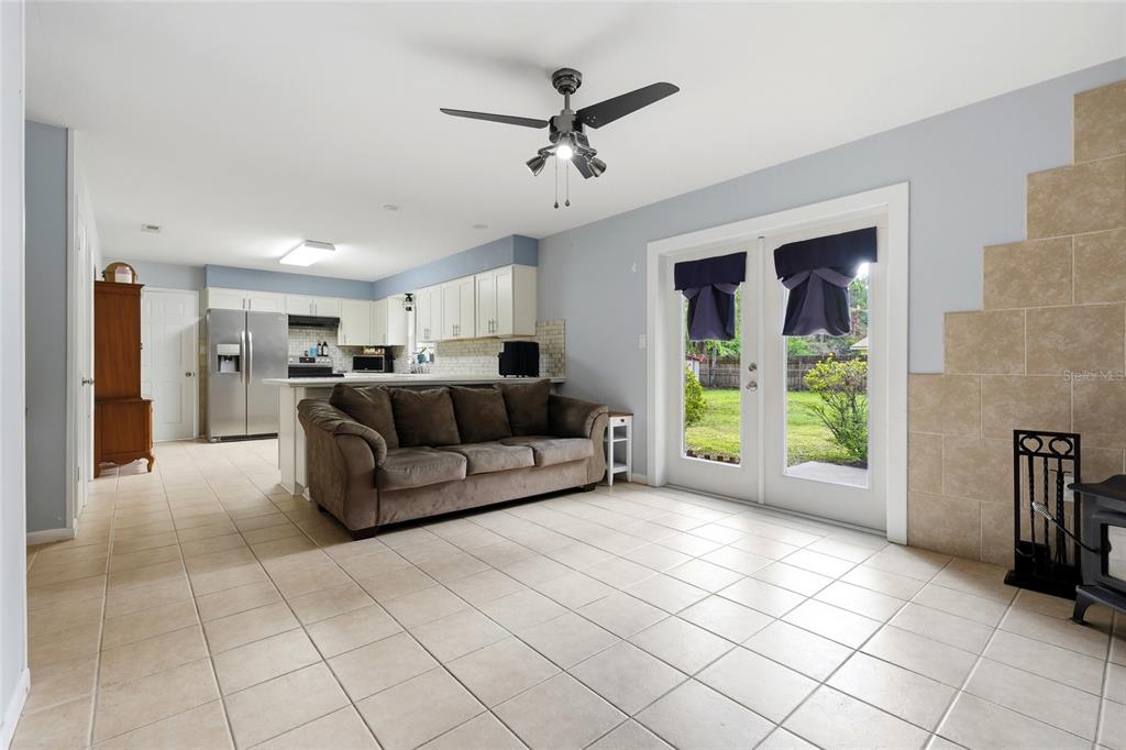 A living room with tile flooring, a brown sofa, and a kitchen in the background — 5 SW 41ST STREET, GAINESVILLE, FL