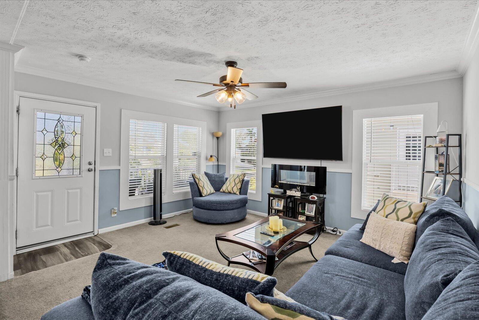 A living room features blue walls, a large sofa, a swivel chair, and a wall-mounted television — 82 Sandhill Boulevard, Fort Pierce FL 34982, FORT PIERCE, FL