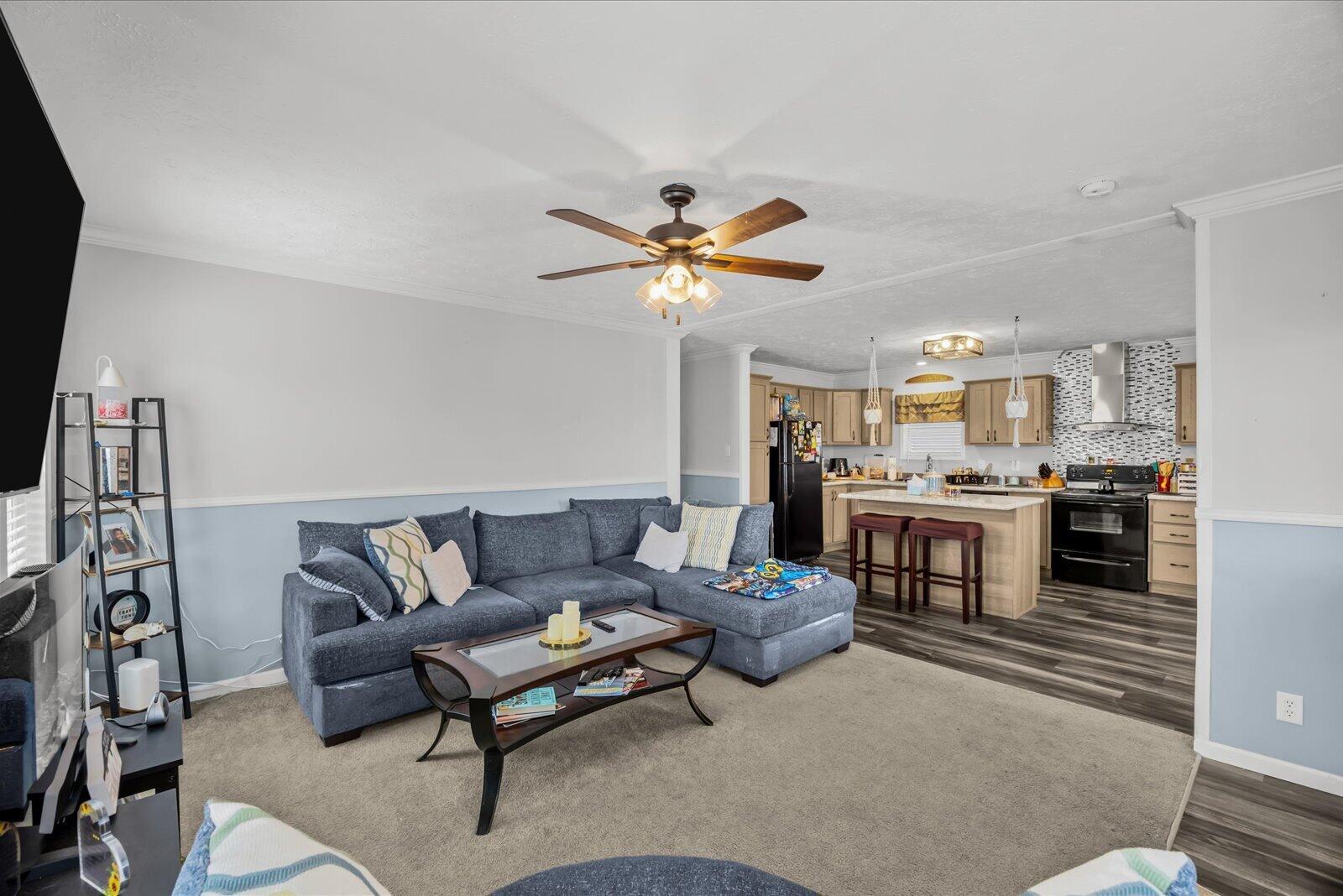A living room with a blue sectional sofa opens into a kitchen with light wood cabinets — 82 Sandhill Boulevard, Fort Pierce FL 34982, FORT PIERCE, FL