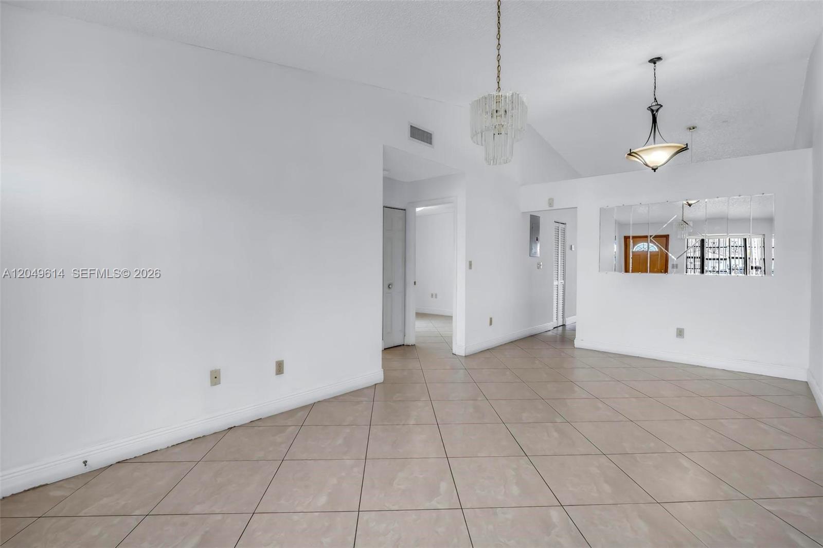An empty room with white walls, beige tile flooring, and two hanging light fixtures — 8871 NW 114th St, Hialeah Gardens FL 33018, HIALEAH GARDENS, FL
