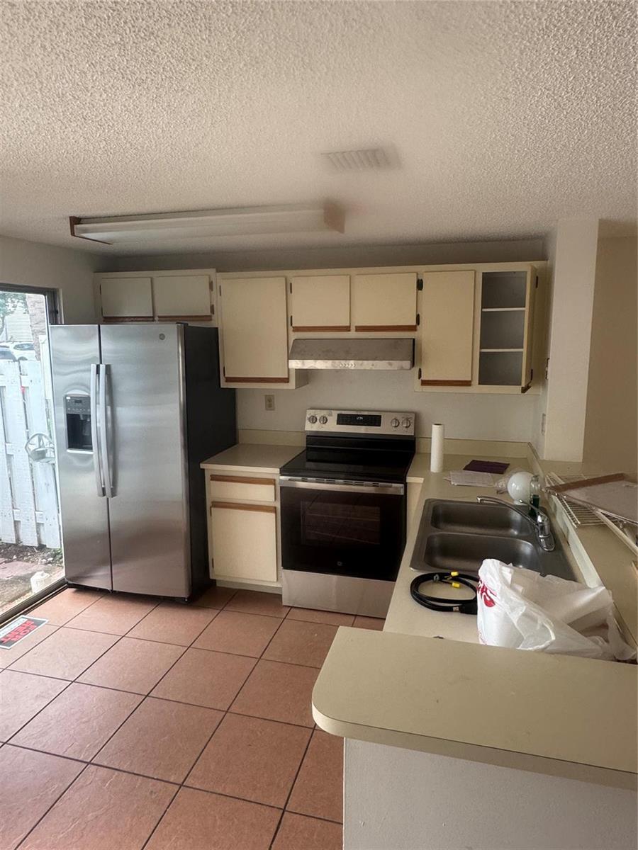 A kitchen features stainless steel appliances, off-white cabinets, a double sink, and tiled flooring — 2845 NE 15th Street, Pompano Beach FL 33062, POMPANO BEACH, FL