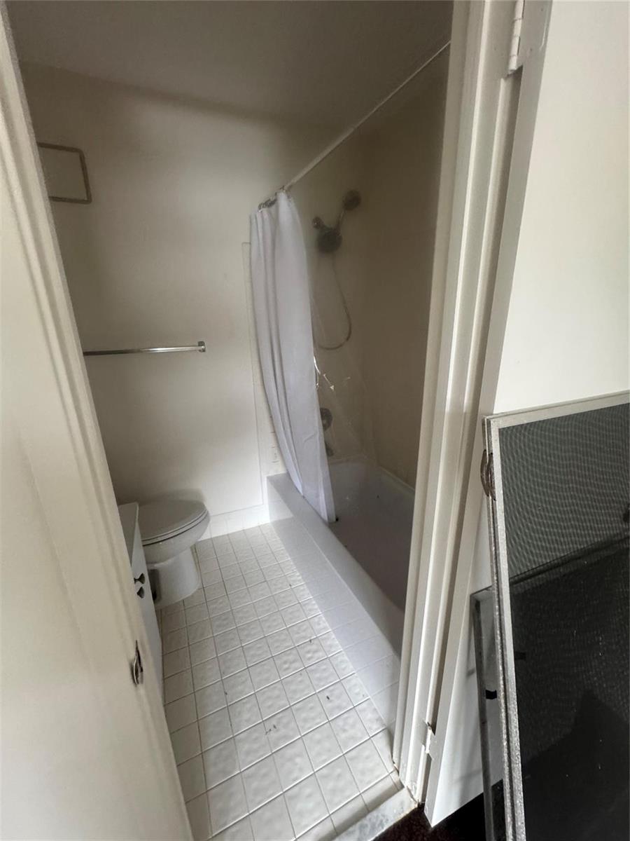 A small bathroom features a white tiled floor, a toilet, and a shower-tub combination — 2845 NE 15th Street, Pompano Beach FL 33062, POMPANO BEACH, FL