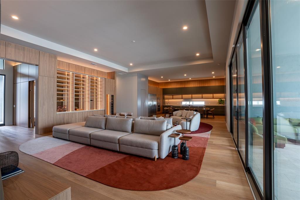A modern open-concept living room features a large sectional sofa, a multi-colored rug, and wood cabinetry — 15125 PENDIO DRIVE, MONTVERDE, FL