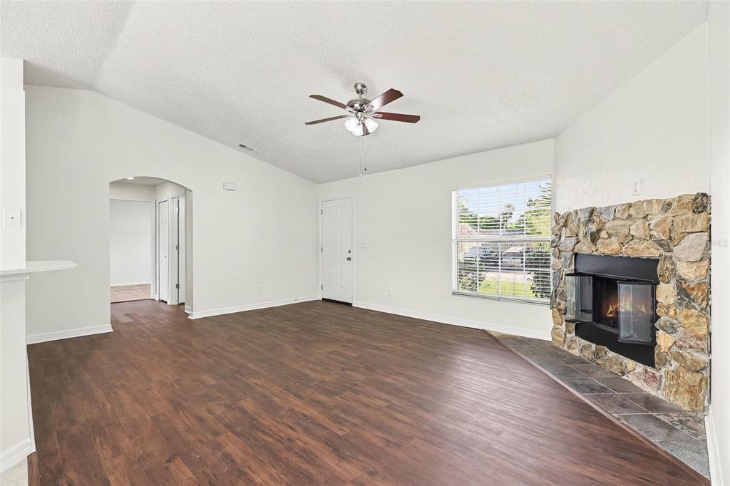 A living room with wood-look flooring, a stone fireplace, and a ceiling fan — 6236 BRANDT STREET, COCOA, FL