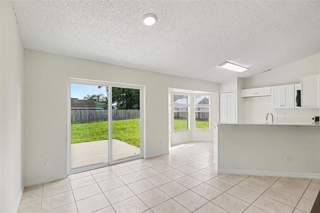 A tiled dining area features a sliding glass door, a bay window, and an adjacent kitchen — 6236 BRANDT STREET, COCOA, FL