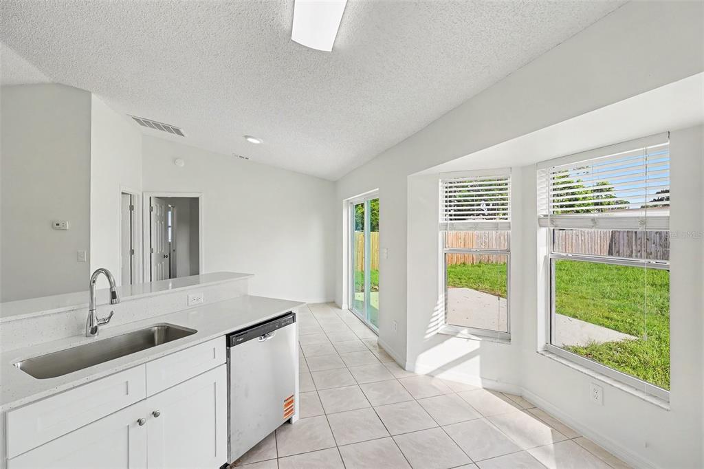 A kitchen with white cabinets, a stainless steel sink, and a sliding glass door — 6236 BRANDT STREET, COCOA, FL
