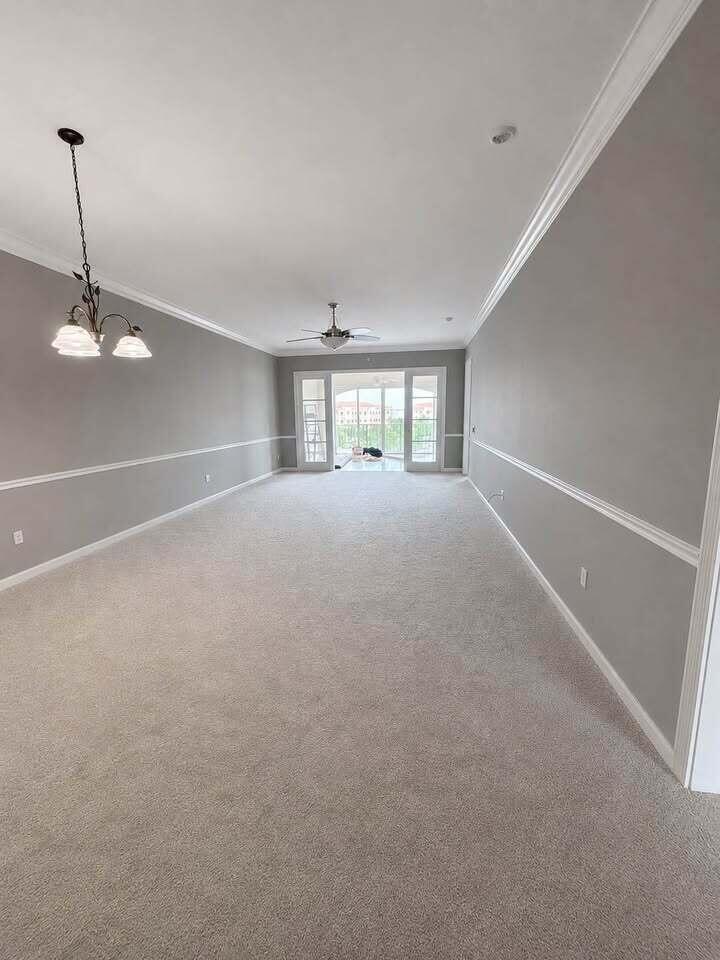 A long, empty room features gray walls with white chair rail molding and carpeted flooring — 5 Harbour Isle Drive E, Fort Pierce FL 34949, FORT PIERCE, FL