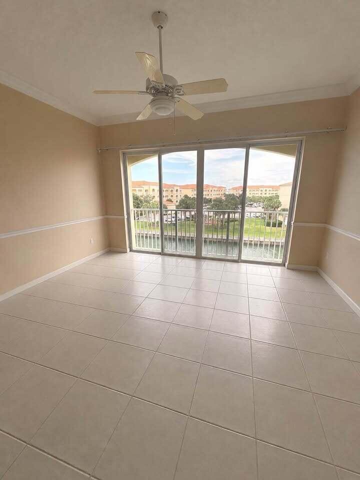 An empty room with beige walls, tile flooring, a ceiling fan, and sliding glass balcony doors — 5 Harbour Isle Drive E, Fort Pierce FL 34949, FORT PIERCE, FL