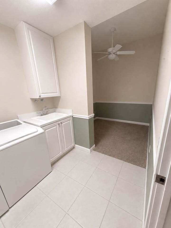 A laundry room with a utility sink, white cabinets, and an adjacent carpeted flex space — 5 Harbour Isle Drive E, Fort Pierce FL 34949, FORT PIERCE, FL