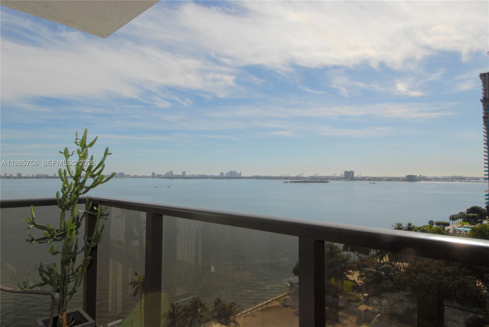 A balcony view overlooks a large body of water with a distant city skyline — 600 NE 36th St # 1212, Miami FL 33137, MIAMI, FL