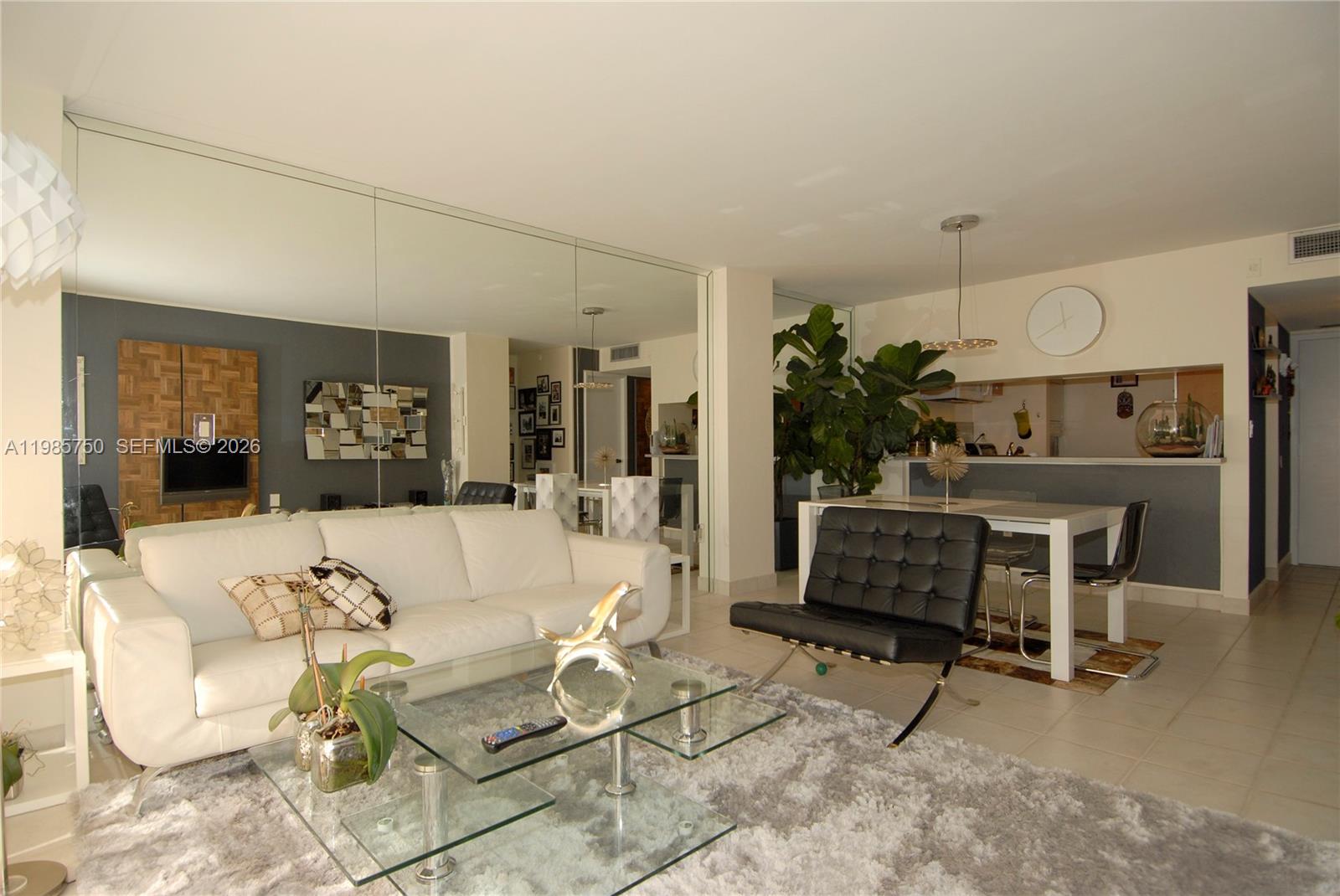 A living room features a white sofa, glass coffee table, and a mirrored wall — 600 NE 36th St # 1212, Miami FL 33137, MIAMI, FL
