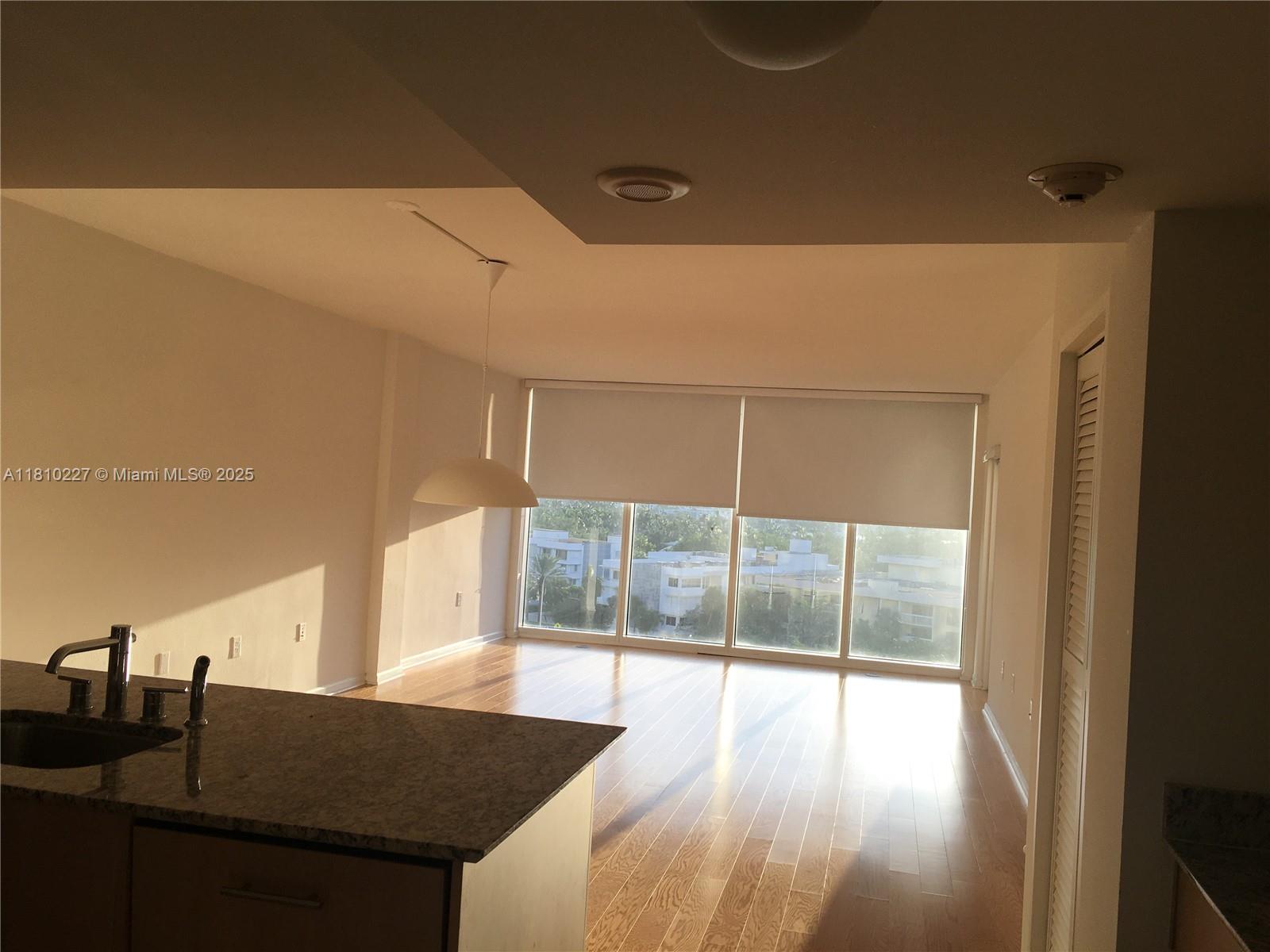 An open-concept living area features hardwood floors, a granite kitchen island, and floor-to-ceiling windows — 10275 Collins Ave # 628, Bal Harbour FL 33154, BAL HARBOUR, FL