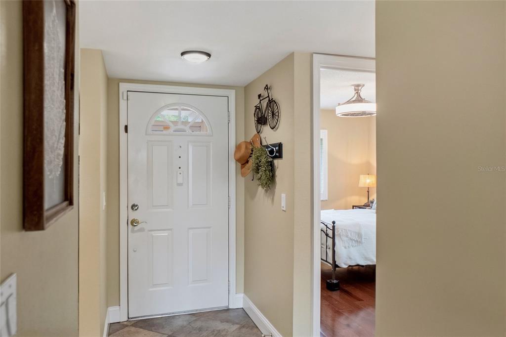 An entryway features a white front door, tile flooring, and a view into a bedroom — 4242 MADEIRA COURT UNIT 3315, SARASOTA, FL