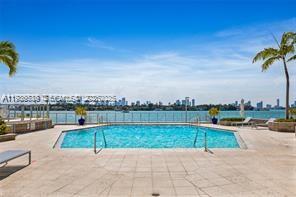 A swimming pool overlooks a bay with a city skyline in the distance — 800 West Ave # 523, Miami Beach FL 33139, MIAMI BEACH, FL