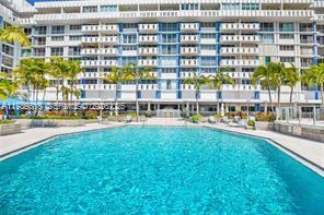 A large swimming pool sits in front of a multi-story white apartment building with balconies — 800 West Ave # 523, Miami Beach FL 33139, MIAMI BEACH, FL