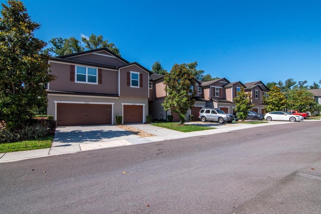 A kitchen features wooden cabinets, granite countertops, a breakfast bar with stools, and tile flooring — 5368 SYLVESTER LOOP, TAMPA, FL