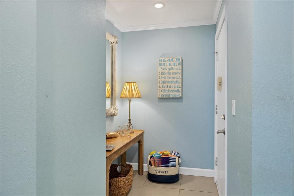 A light blue entryway features a wooden console table, a decorative sign, and a towel basket — 4325 GULF OF MEXICO DRIVE UNIT 208, LONGBOAT KEY, FL