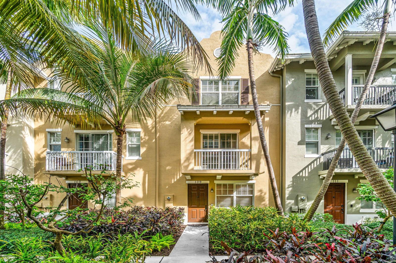 A three-story tan townhouse with balconies, palm trees, and a landscaped walkway in front — 109 E Coda Circle, Delray Beach FL 33444, DELRAY BEACH, FL