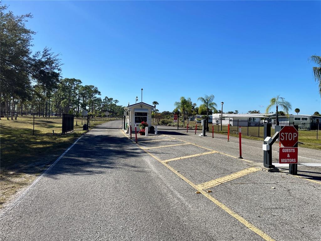 A gated entrance features a guardhouse, a stop sign, and a paved driveway — 6452 FLEETWOOD COURT, NORTH PORT, FL