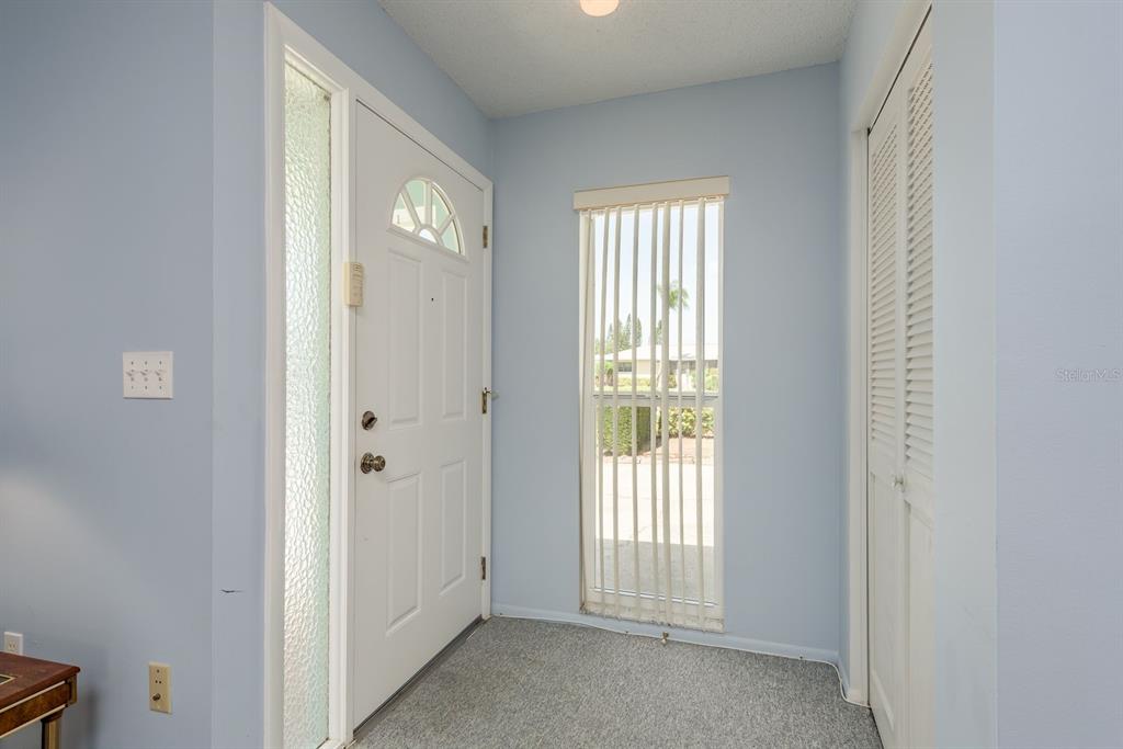 An entryway features a white front door, a side window, and a louvered closet door — 2738 SHERBROOKE LANE UNIT C, PALM HARBOR, FL