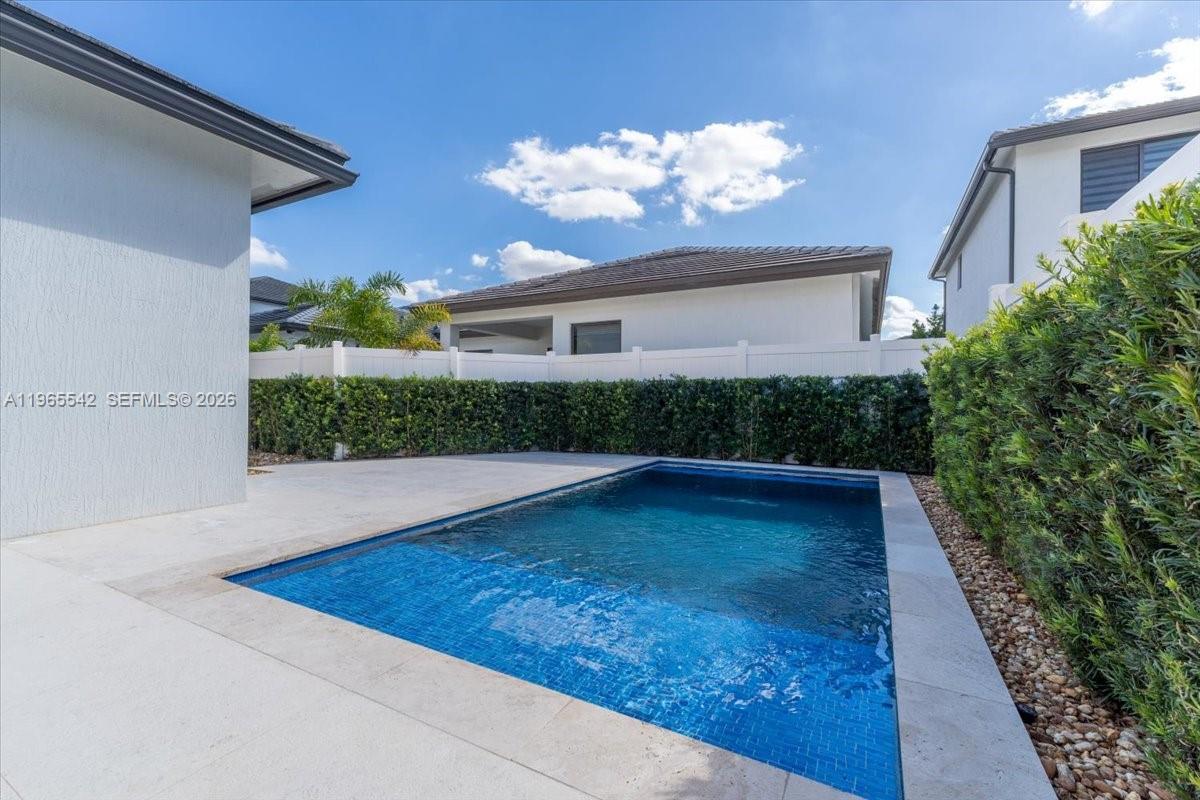 A rectangular swimming pool is situated in a backyard patio area enclosed by hedges — 8096 NW 48th Ter, Doral FL 33166, DORAL, FL
