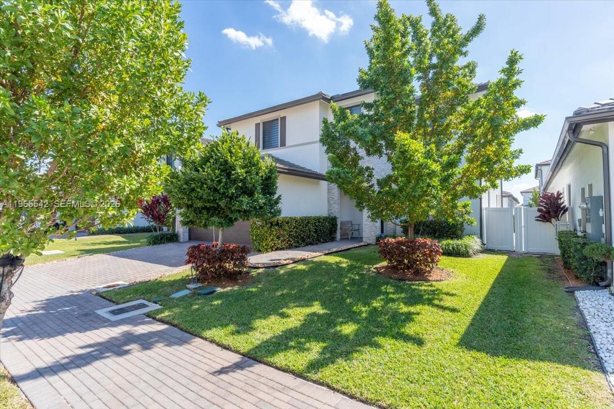 A two-story house with a paved driveway, green lawn, and mature trees in the front — 8096 NW 48th Ter, Doral FL 33166, DORAL, FL