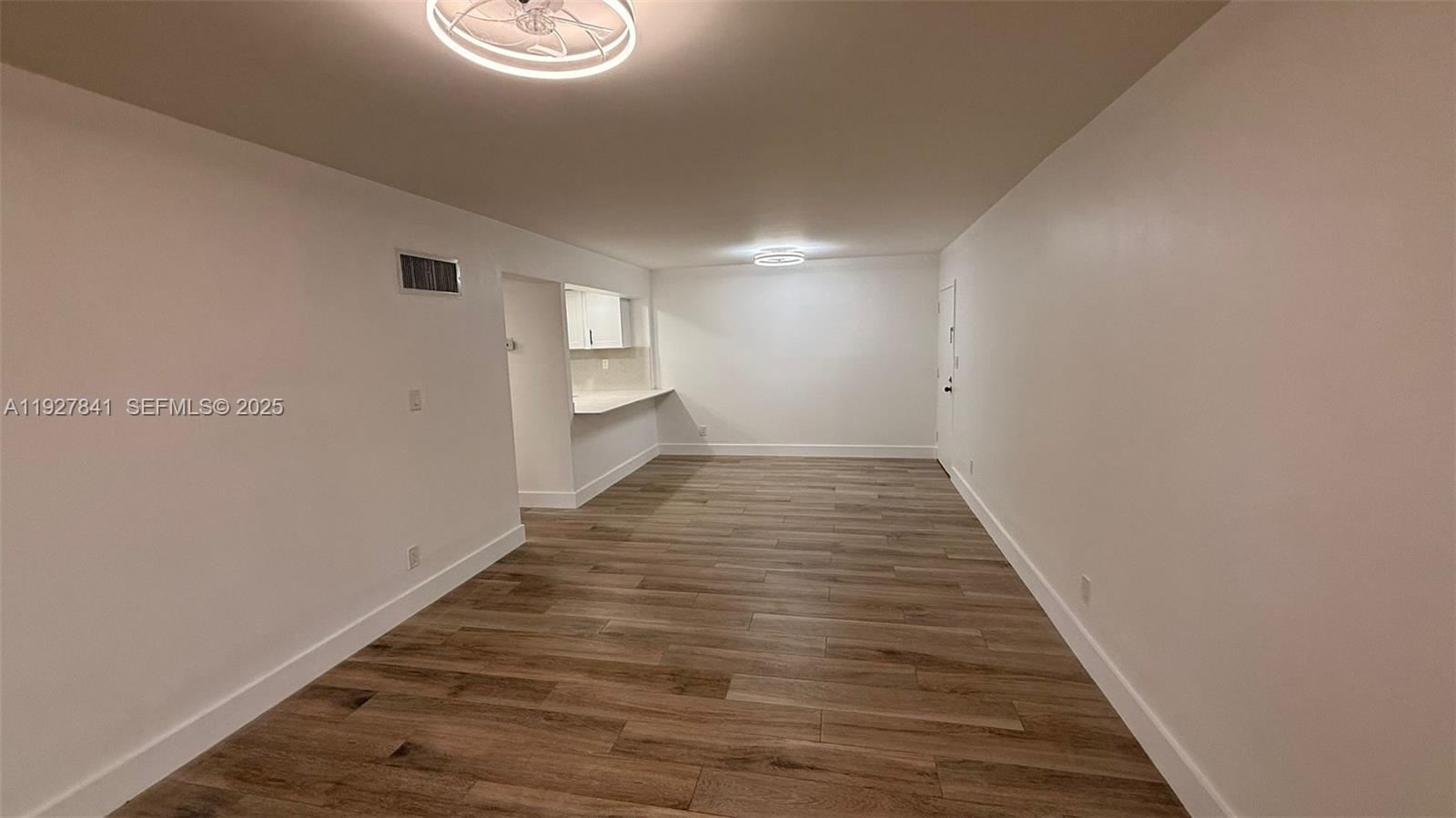 This room features light-colored walls, wood-look flooring, a ceiling fan, and an open kitchen area — 5845 Washington St # 65, Hollywood FL 33023, HOLLYWOOD, FL