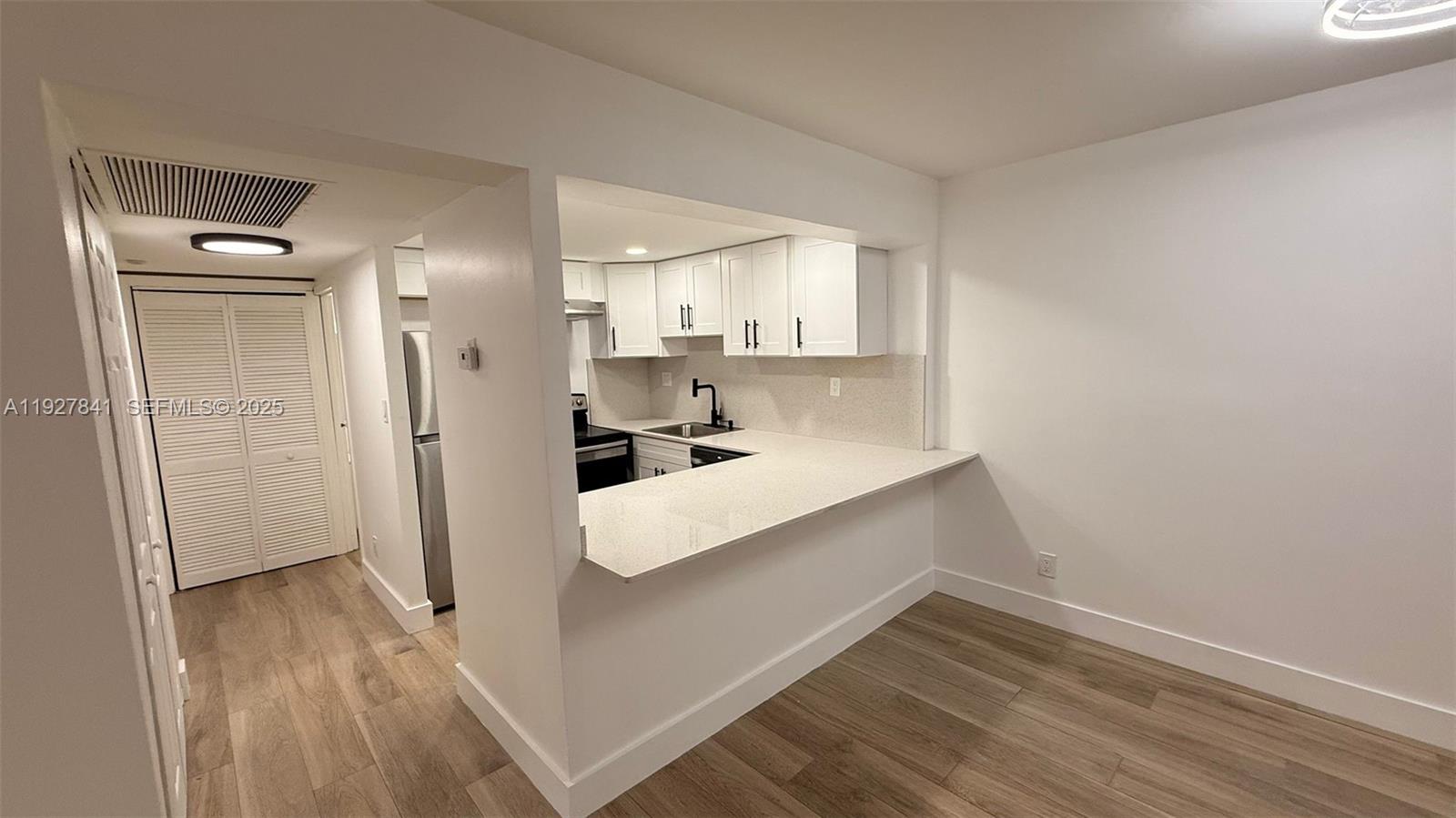 A kitchen with white cabinets and a breakfast bar opens into a dining area — 5845 Washington St # 65, Hollywood FL 33023, HOLLYWOOD, FL