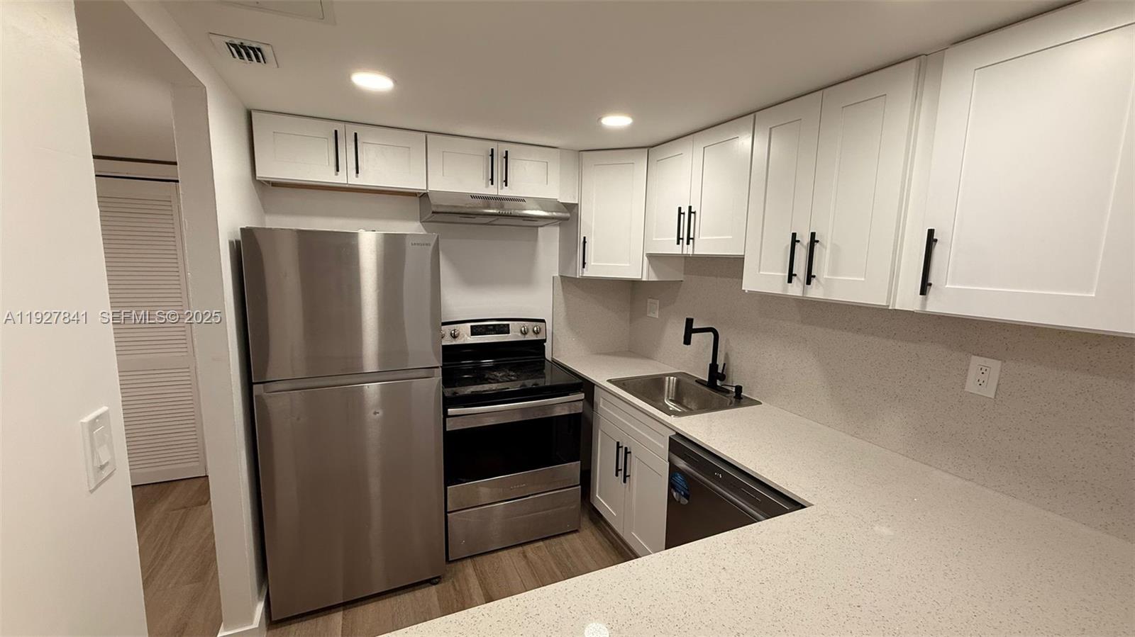 A kitchen features white cabinets, stainless steel appliances, and light-colored countertops — 5845 Washington St # 65, Hollywood FL 33023, HOLLYWOOD, FL