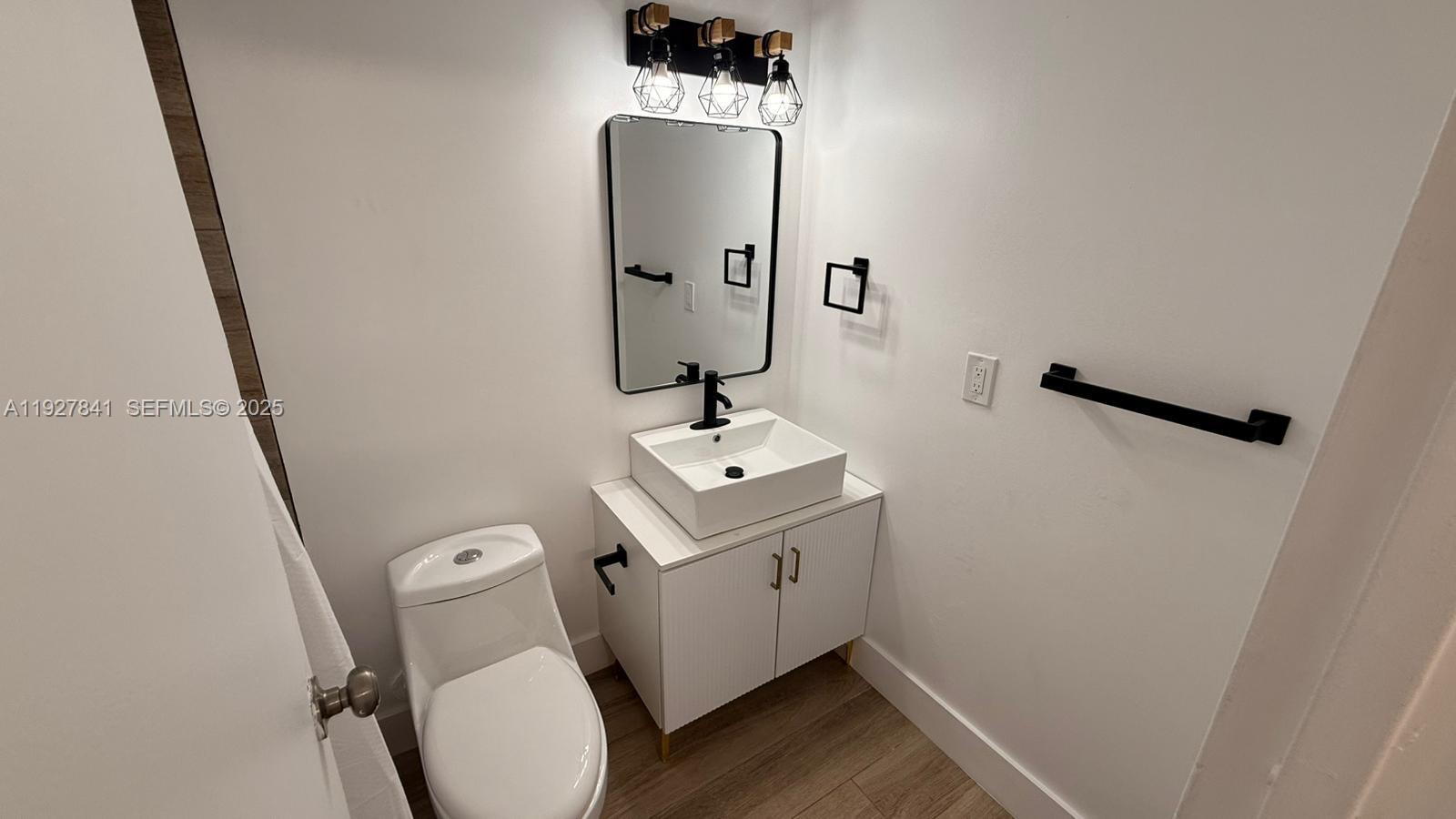 A small bathroom features a white vanity with a vessel sink, toilet, and black fixtures — 5845 Washington St # 65, Hollywood FL 33023, HOLLYWOOD, FL