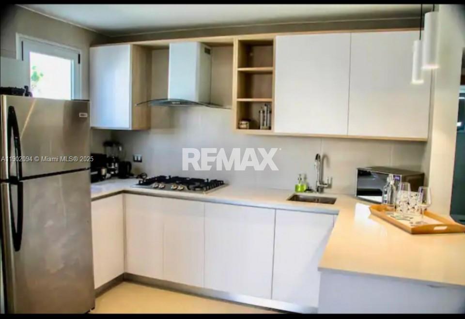 A modern kitchen features white cabinets, stainless steel appliances, and a light-colored countertop — El cortesito Punta Cana # 1, PU, PU