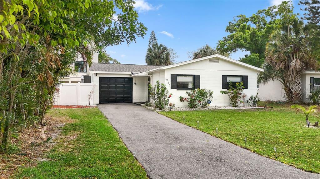 A single-story white house with a black garage door and a paved driveway — 1920 NEW HAMPSHIRE AVENUE NE, ST PETERSBURG, FL
