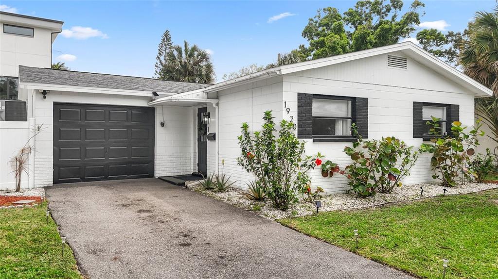 A white single-story house with a black garage door and black window shutters — 1920 NEW HAMPSHIRE AVENUE NE, ST PETERSBURG, FL