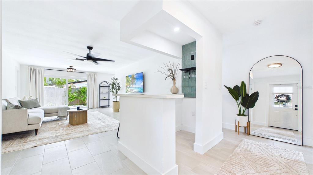 A living room features a white bar, tiled floors, a ceiling fan, and a mirror — 1920 NEW HAMPSHIRE AVENUE NE, ST PETERSBURG, FL