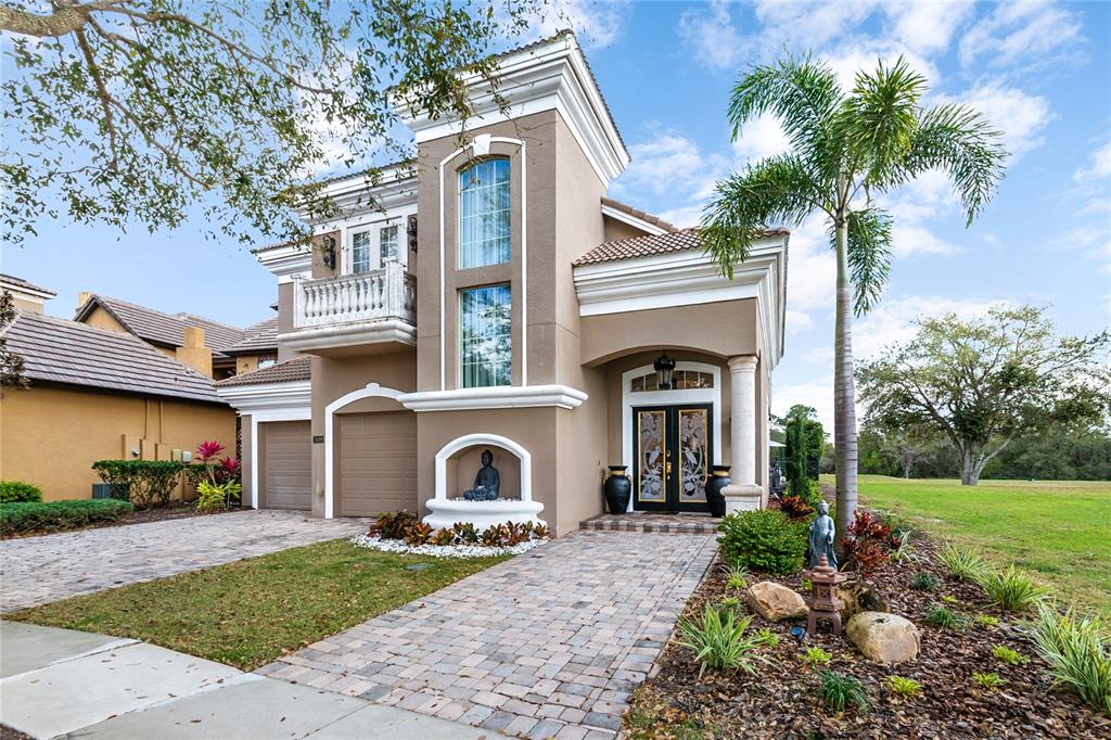 A two-story tan stucco house features a paved driveway, a balcony, and a front entrance — 7409 GATHERING COURT, REUNION, FL