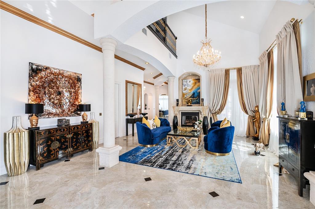 A formal living room features marble floors, blue velvet furniture, a fireplace, and a chandelier — 7409 GATHERING COURT, REUNION, FL