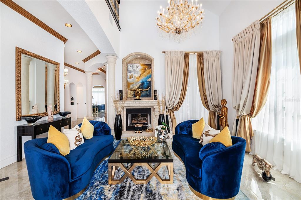 A formal living room features two blue velvet sofas, a fireplace, and a crystal chandelier — 7409 GATHERING COURT, REUNION, FL