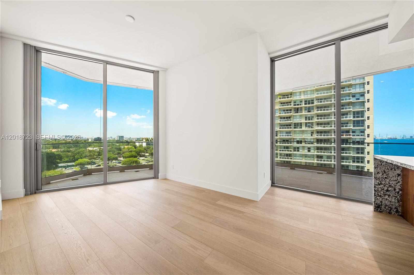 An empty room features light wood flooring, white walls, and floor-to-ceiling windows with balcony access — 175 SE 25 RD # 804, Miami FL 33129, MIAMI, FL