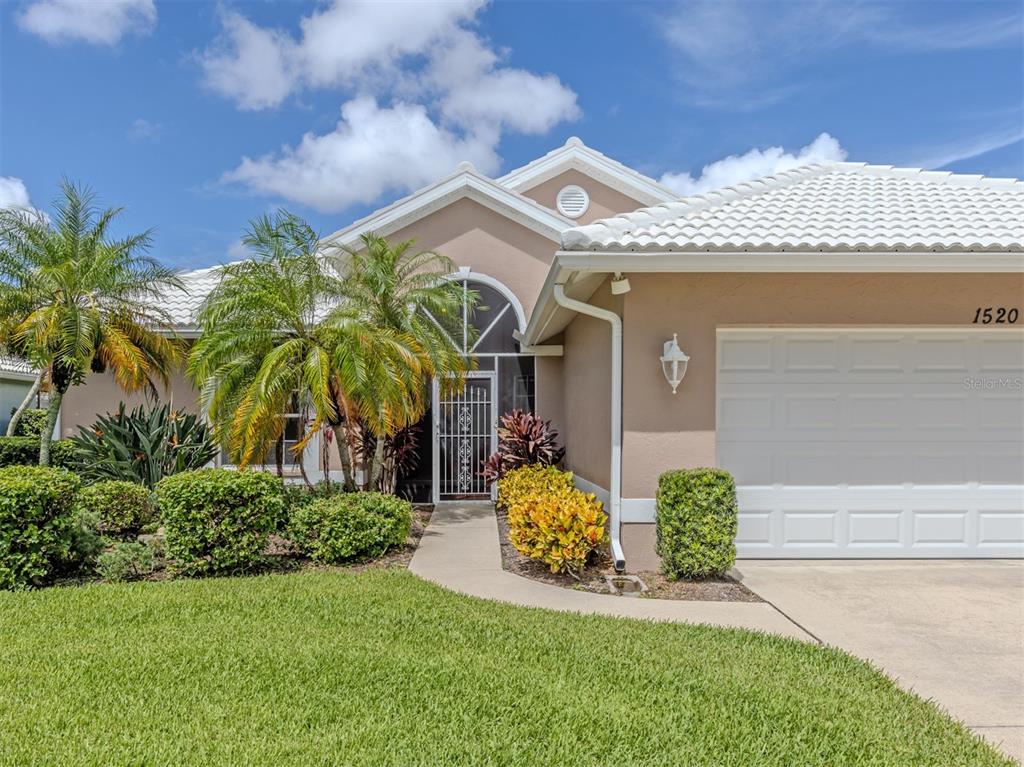 A single-story house with a beige exterior, white tile roof, and a front-facing garage — 1520 JASPER COURT, VENICE, FL