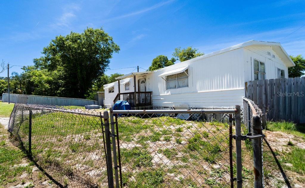 A white mobile home sits behind a chain-link fence on a sunny day — 2900 STATE ROAD 11, DELAND, FL
